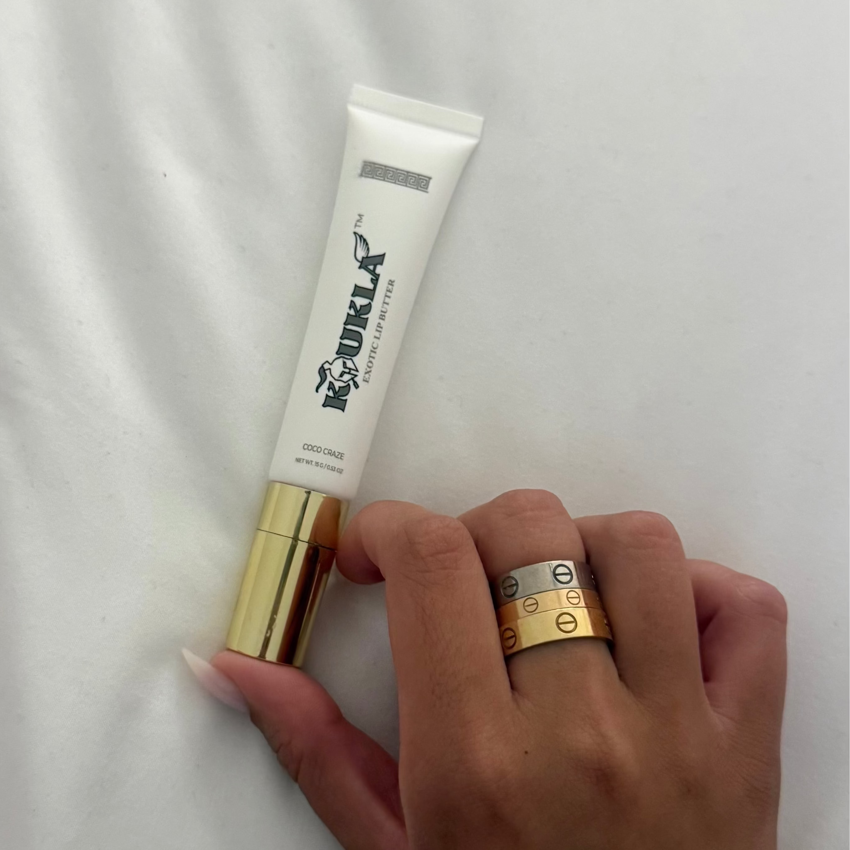 Hand holding a tube of Koukla on a white background