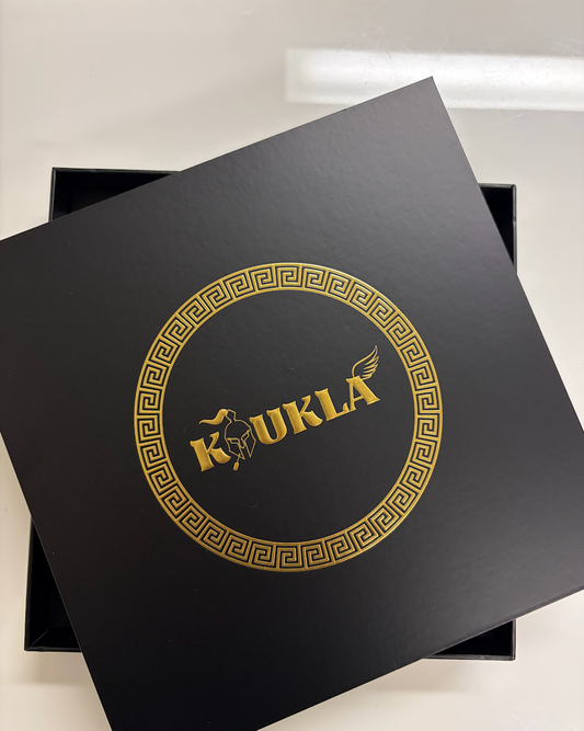 Black box with gold koukla logo on a white background